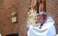 t. Mary pastor Father Kevin Huber raises the monstrance as he leads benediction in June 2023.